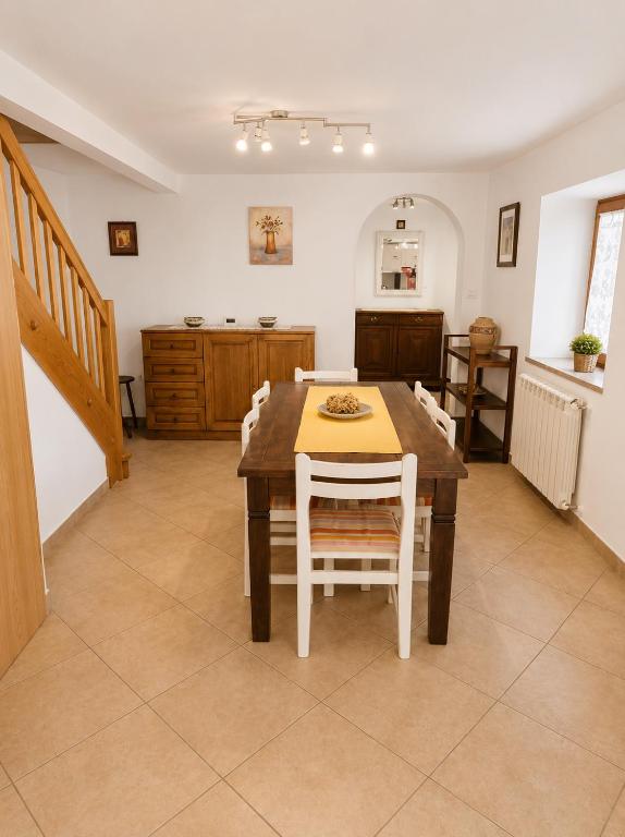 a dining room with a wooden table and white chairs at Hisa pri Ovcicevih in Komen
