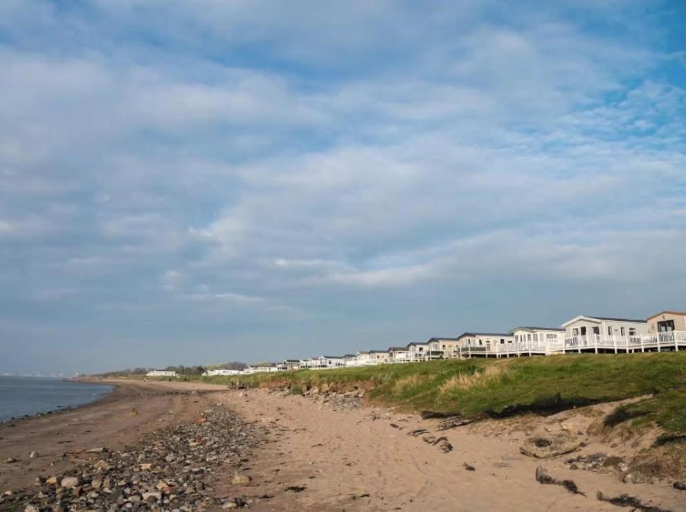 a sandy beach with houses in the background and the ocean at Craig Tara Beach Lodge in Ayr