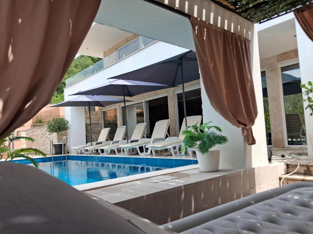a house with a swimming pool with chairs and umbrellas at Vila Olive 51 in Tivat