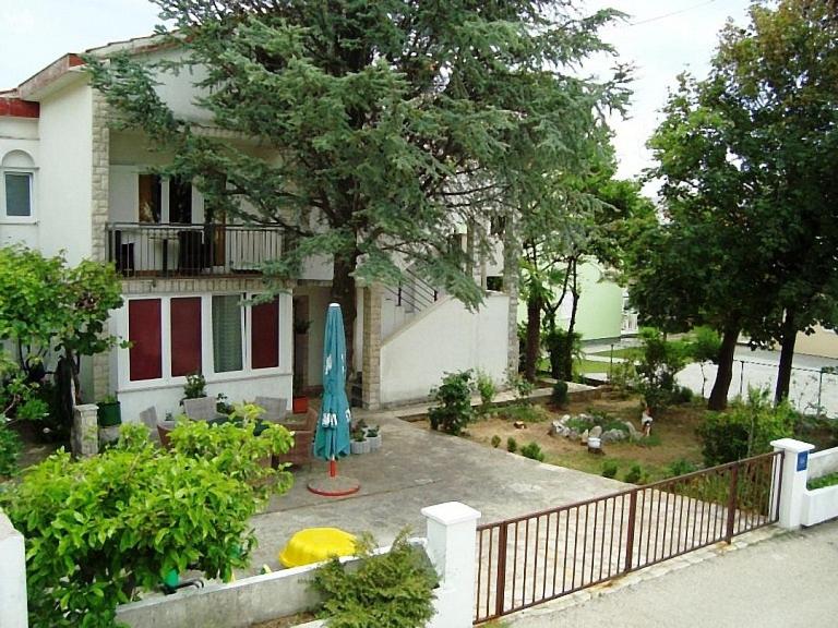 a house with a yard with a umbrella in front of it at Apartman Marija Krok in Baška