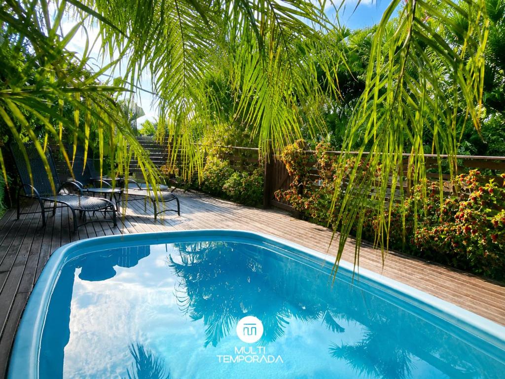 a swimming pool in a backyard with a palm tree at Pousada Coração do Rosa - Praia do Rosa/SC in Praia do Rosa