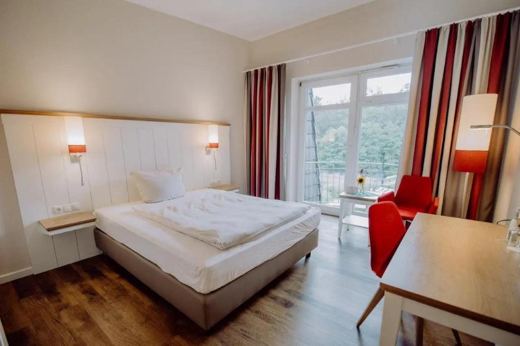 a hotel room with a bed and a red chair at Pescheks Tagungshaus Walsrode in Walsrode