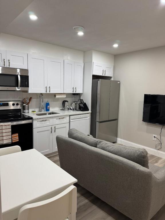 a kitchen with white cabinets and a couch in a room at The Cozy Nook in Cochrane