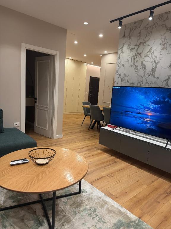 a living room with a large tv and a table at Tirana Lake Bliss Apartment in Sauk