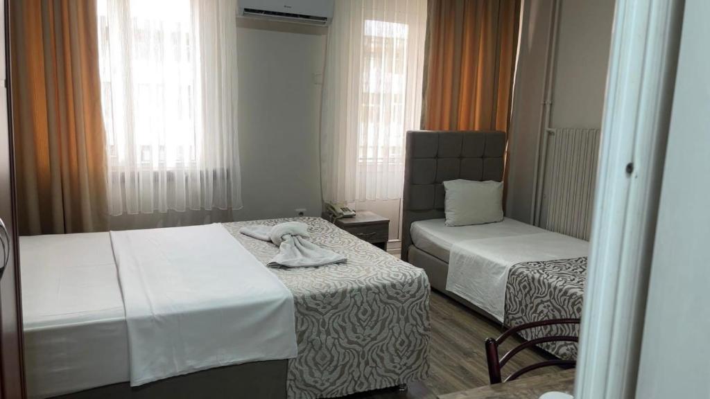 a hotel room with two beds and a chair at Kenedi Otel in Altındağ