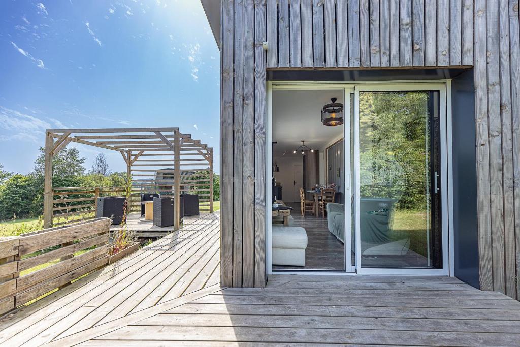 a house with a wooden deck with a glass door at Le Container de Jeff - Maison bois, grand jardin in Uzel