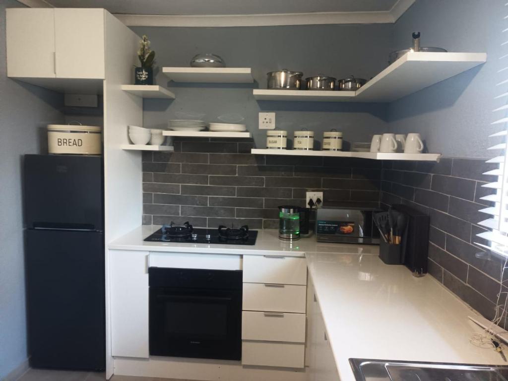 a kitchen with white cabinets and a black refrigerator at Lifeshed Guest Home in Johannesburg