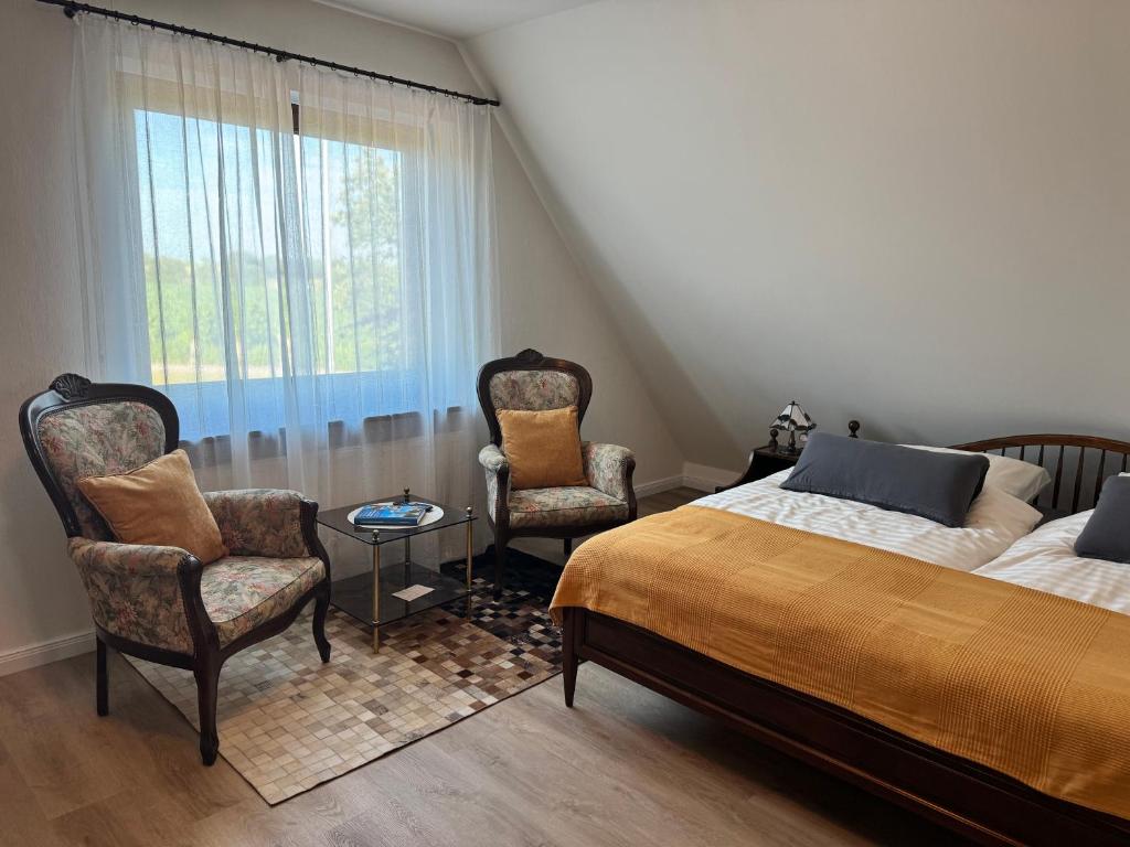 a bedroom with a bed and two chairs and a window at Ferienwohnung Klahn Neue Tiefe in Neue Tiefe Fehmarn