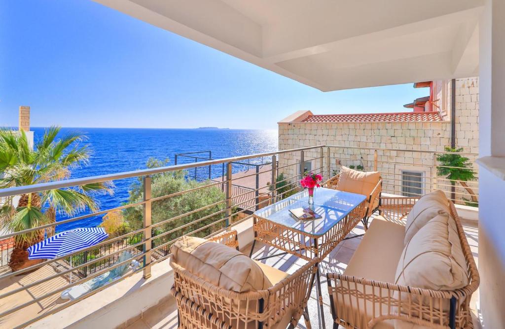a balcony with chairs and a table and the ocean at Panaroma Meis Suits in Kaş