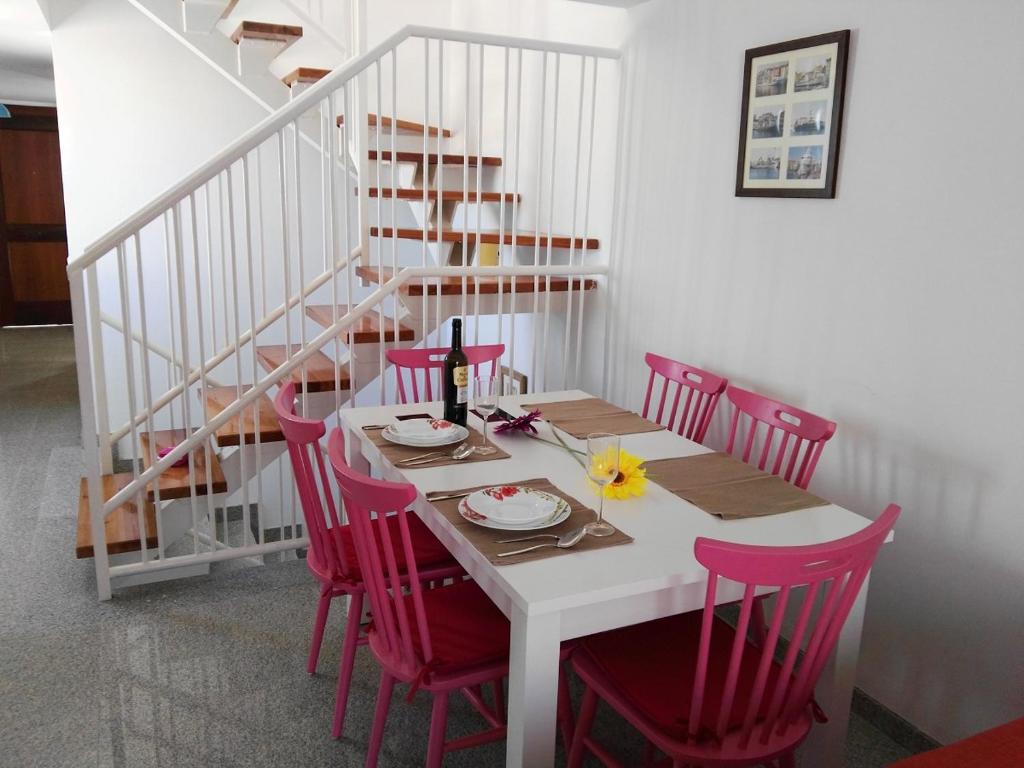 a dining room table with pink chairs and a staircase at Velez Nazari Cambriles in Lújar