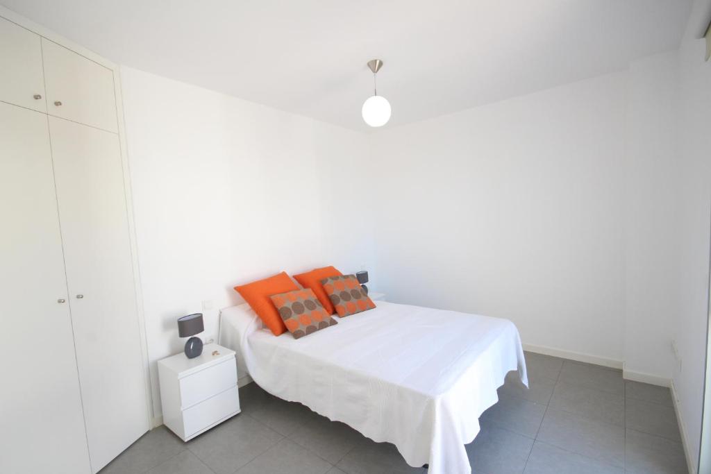 a white bedroom with a bed with orange pillows at Apartment El Medano Sunrises in El Médano