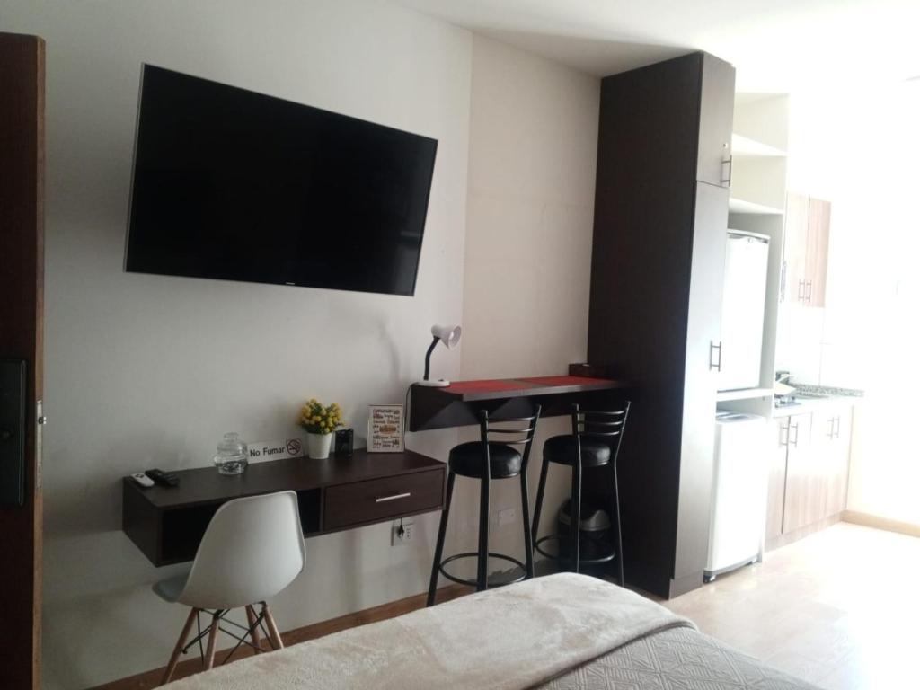 a bedroom with a desk and a television on the wall at Disfruta Cala-Cala in Cochabamba