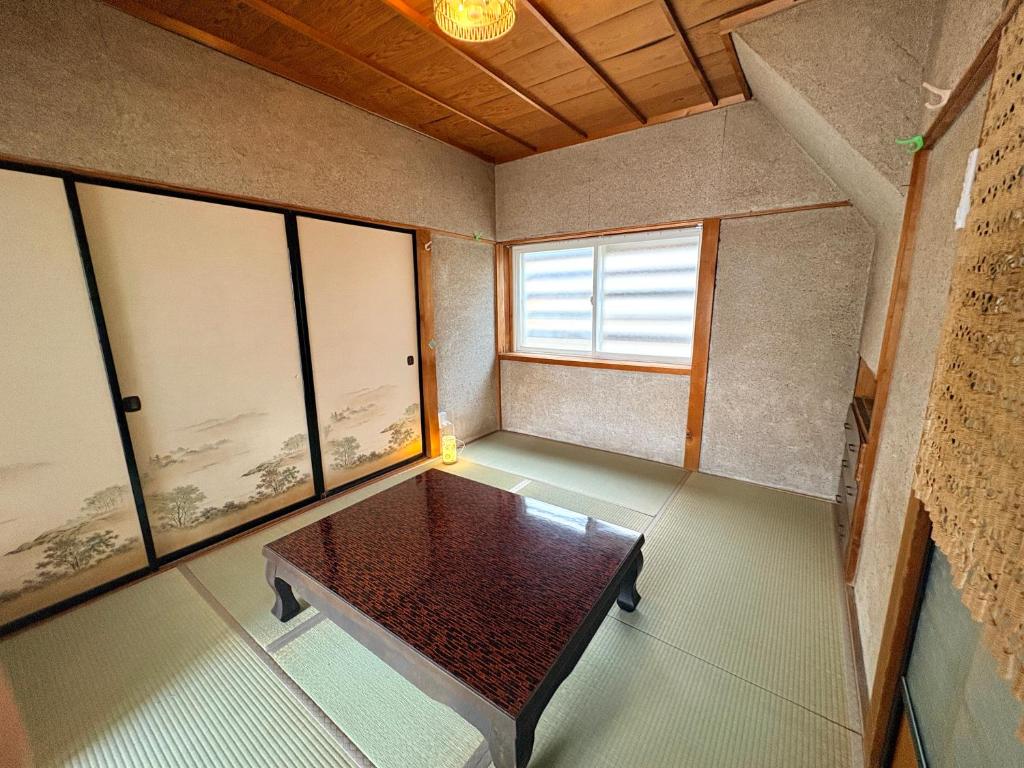 a room with a table in a room with windows at 長峰駅から徒歩3分ゲストハウスオオワニ in Ōwani