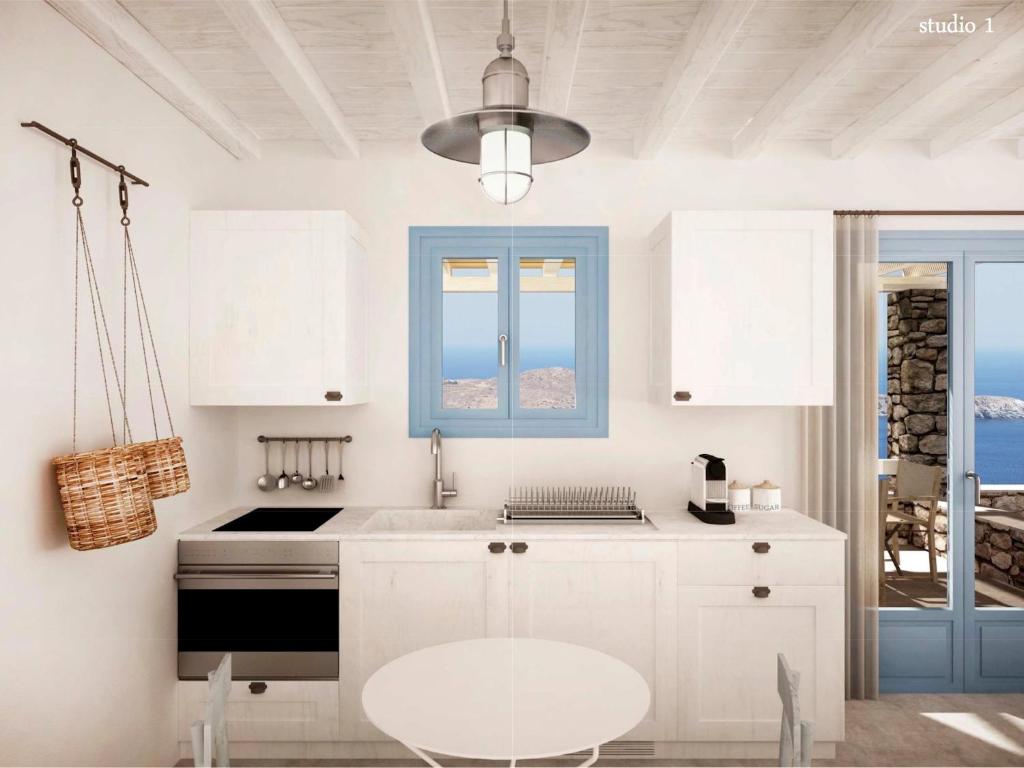 a kitchen with white cabinets and a blue window at Serifos Blue in Rámos