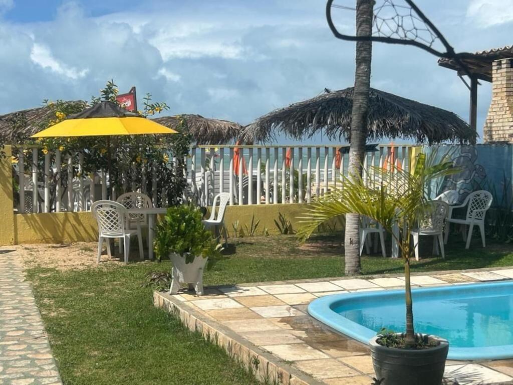 a resort with a pool and chairs and a umbrella at Pousada Girassol Genipabu in Extremóz
