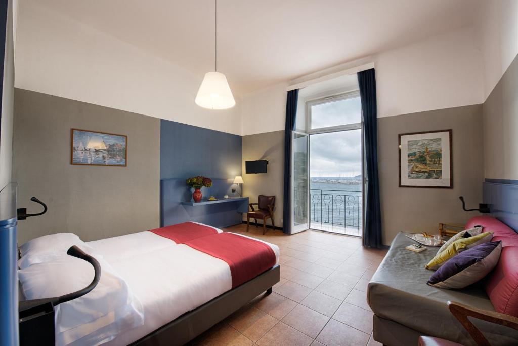 a bedroom with a bed and a couch and a window at Hotel Italia e Lido Rapallo in Rapallo