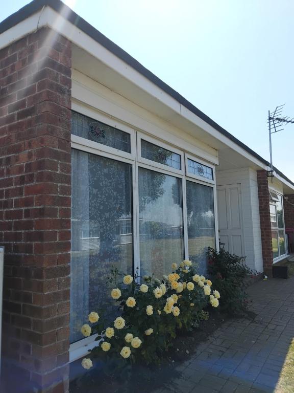 a house with flowers in front of a window at "Trinity" Chalet in Sundowner Hemsby in Hemsby