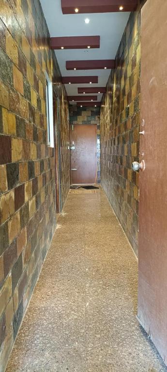 an empty hallway with a brick wall and a door at white sand villa in Tirupporūr