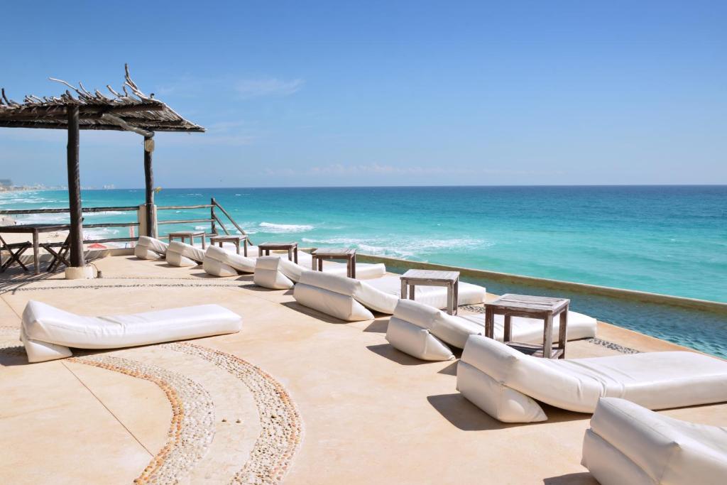 a row of white lounge chairs and tables on the beach at AR Cancun Plaza in Cancún