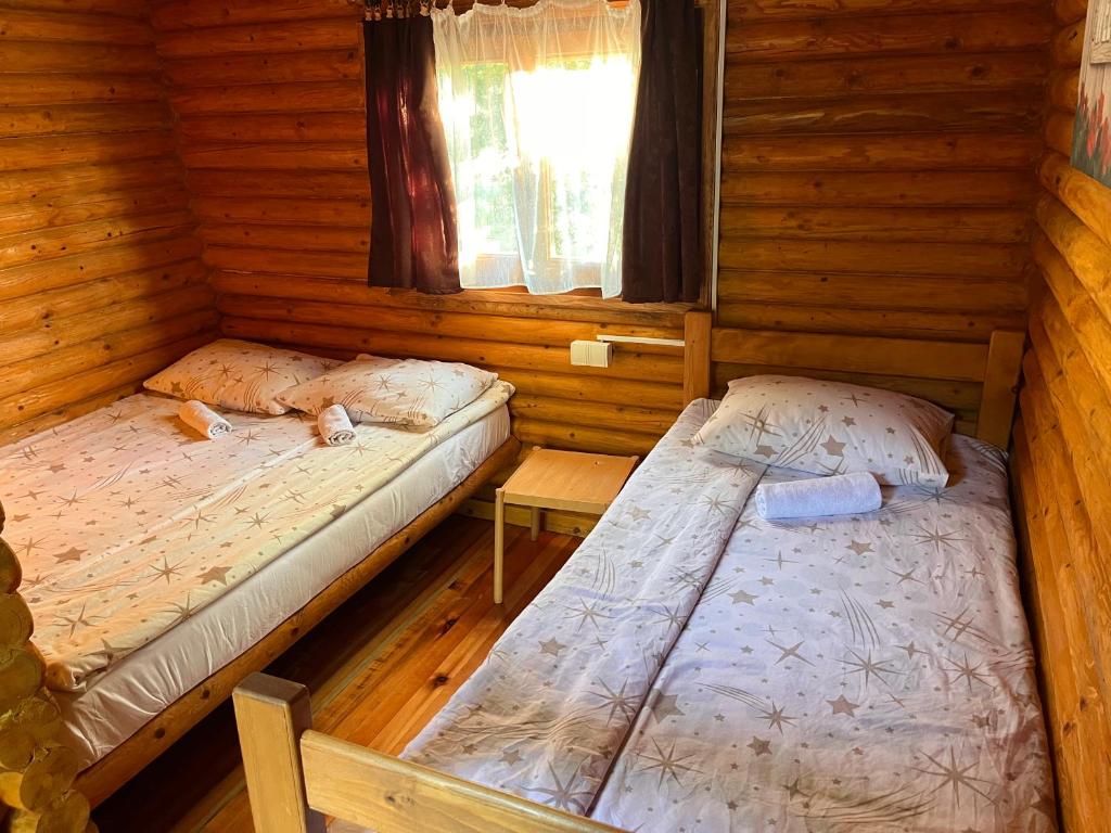 two beds in a room with wooden walls at Rafting Centar Bato in Plužine