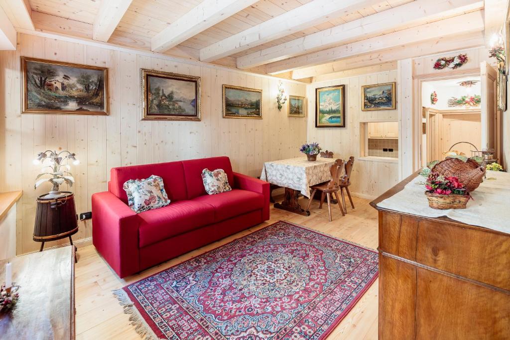 sala de estar con sofá rojo y mesa en Villa Olimpia - Stayincortina en Cortina dʼAmpezzo