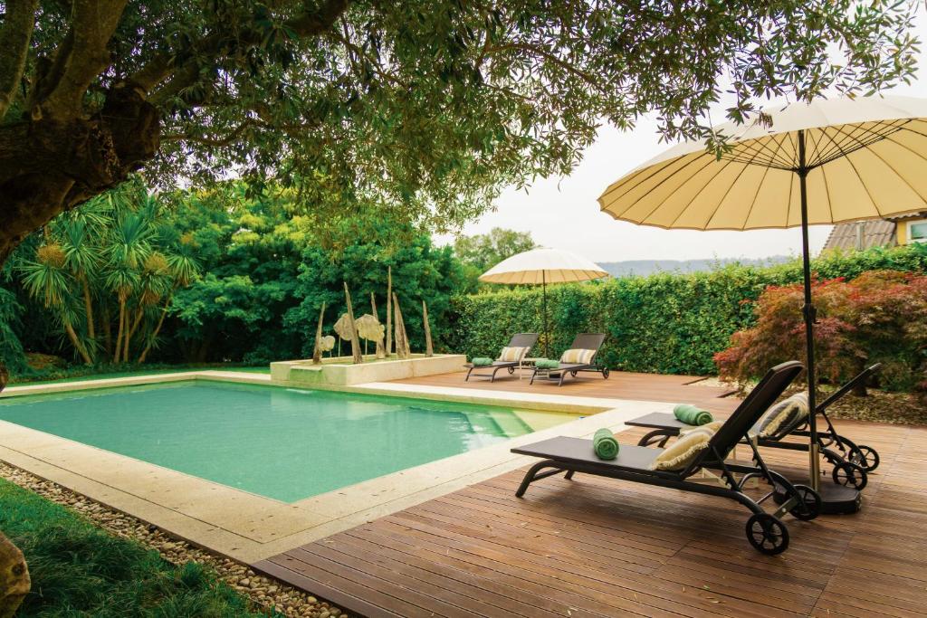 a swimming pool with a chair and an umbrella at Estrepão House in Moreira de Conegos
