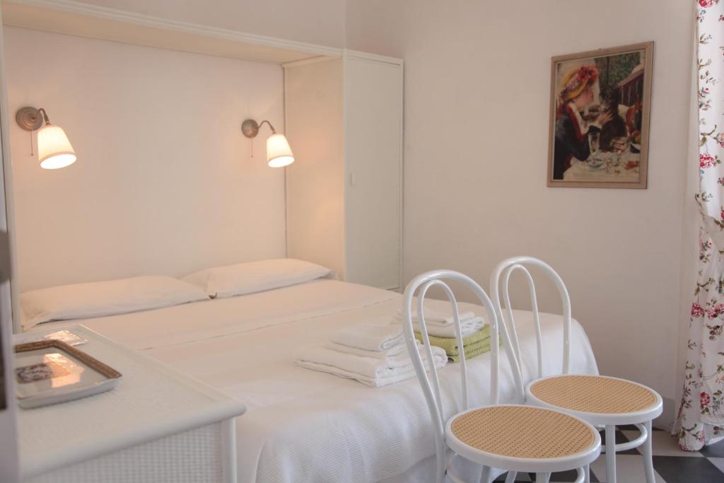 biały pokój z łóżkiem i 2 krzesłami w obiekcie Al vecchio castello w Tropei