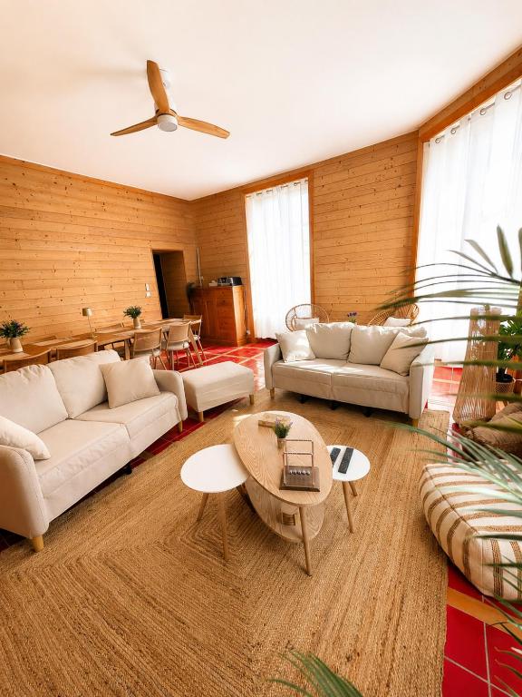 a living room with white couches and a table at Gîte de l'Esplanade-18 min du Puy du Foù-Ventilateurs- Billard- Baby-foot-Fléchettes-Grande maison de bourg spacieuse de 200m2- Famille-Amis-Groupe in Pouzauges