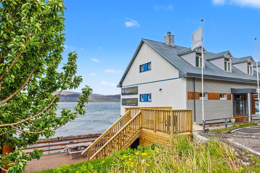 a large white building with a wooden ramp next to a body of water at Hotel West in Patreksfjörður