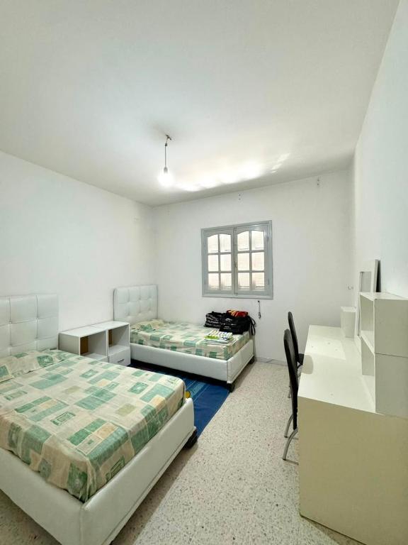 a bedroom with two beds and a desk and a desk at Appartement près de la corniche in Sousse