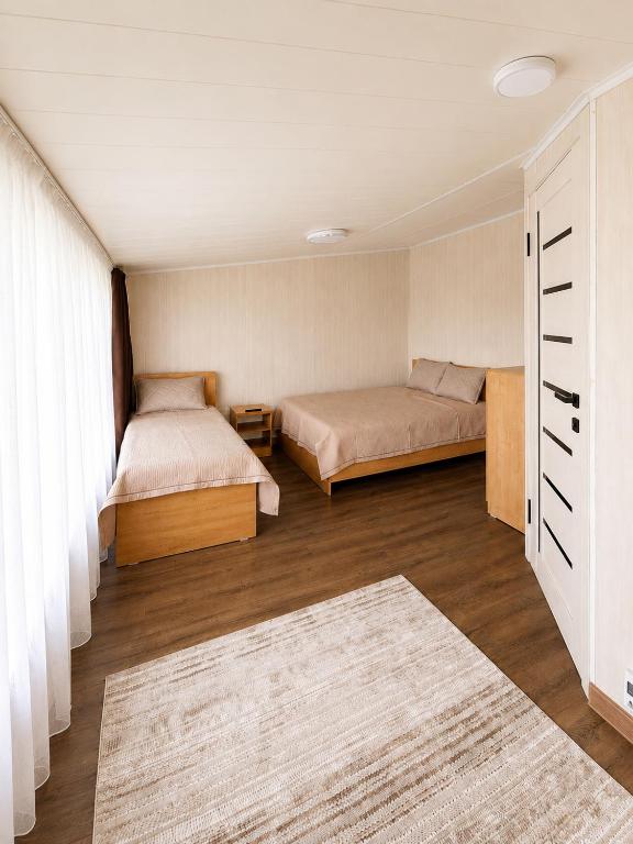a bedroom with two beds and a rug at Valentina`s Guesthouse in Korumdy