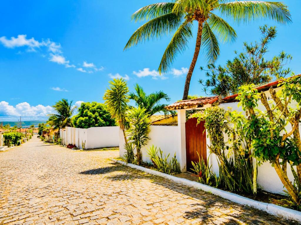 a cobblestone street in front of a house with palm trees at Chalé Rosani in Pipa