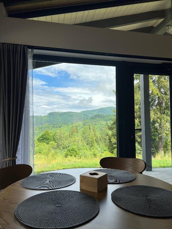 a table with four chairs and a large window at Sviy home in Slavske