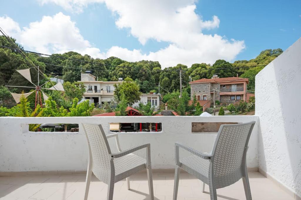 two chairs sitting on a balcony overlooking a city at Dionysus House Lasithi Plateau in Magoulás