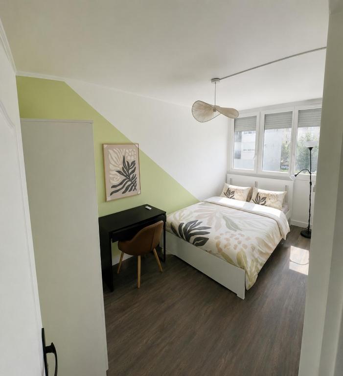 a bedroom with a bed and a desk and a window at Michèle Home in Orly