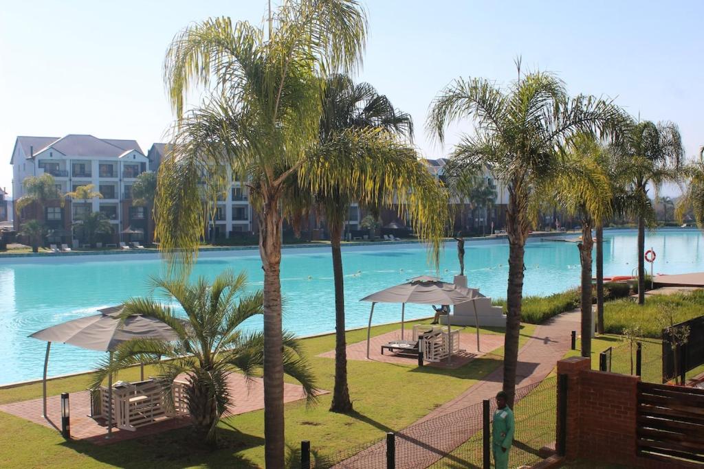 a view of a pool with palm trees and umbrellas at First Gen lagoon facing luxury apartment in Pretoria