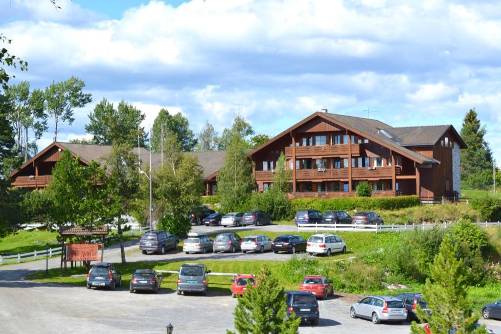 a large wooden building with cars parked in a parking lot at Toten Hotel Sillongen in Eklund