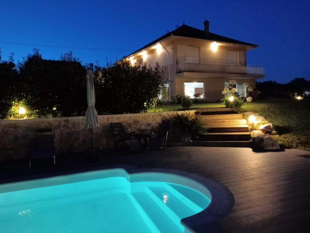 a house with a swimming pool in front of it at night at Lar de Mamita in Cristiñade