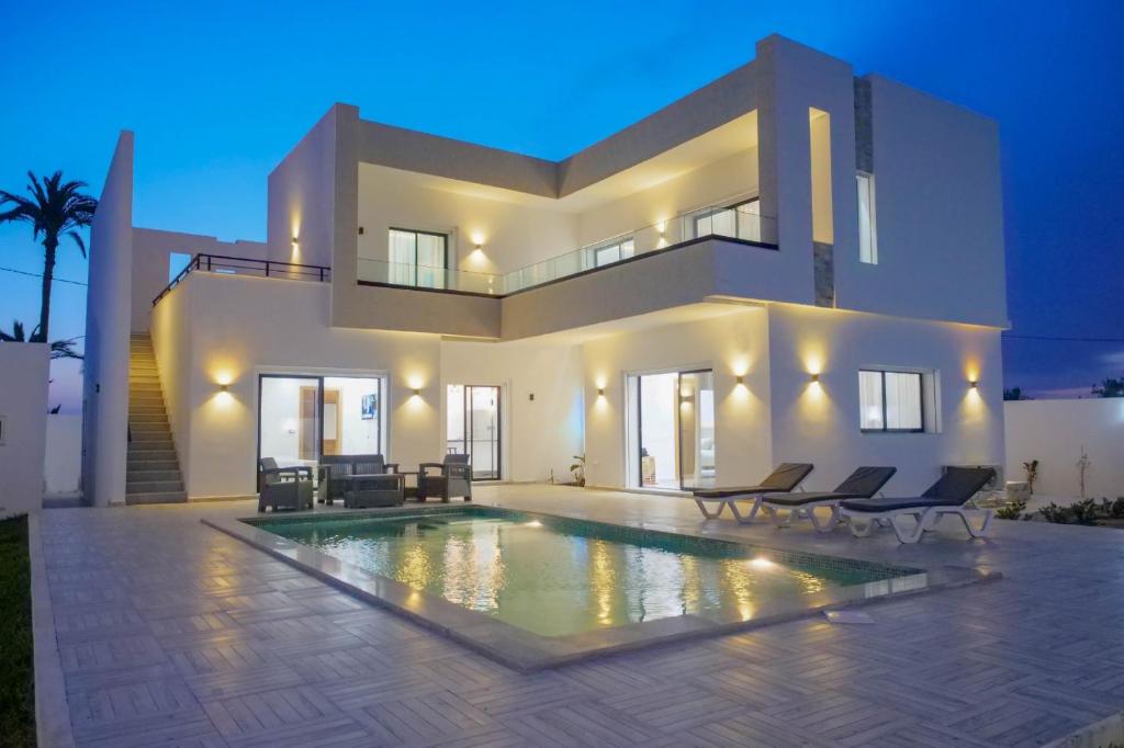 a large white house with a swimming pool in front of it at Villa Ghizen in Fafou