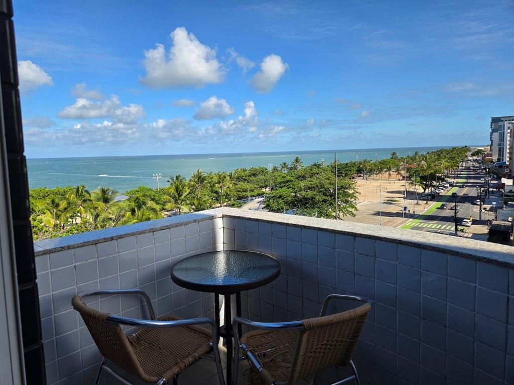 a balcony with a table and chairs and the ocean at Lindo Duplex na orla de Pajuçara in Maceió