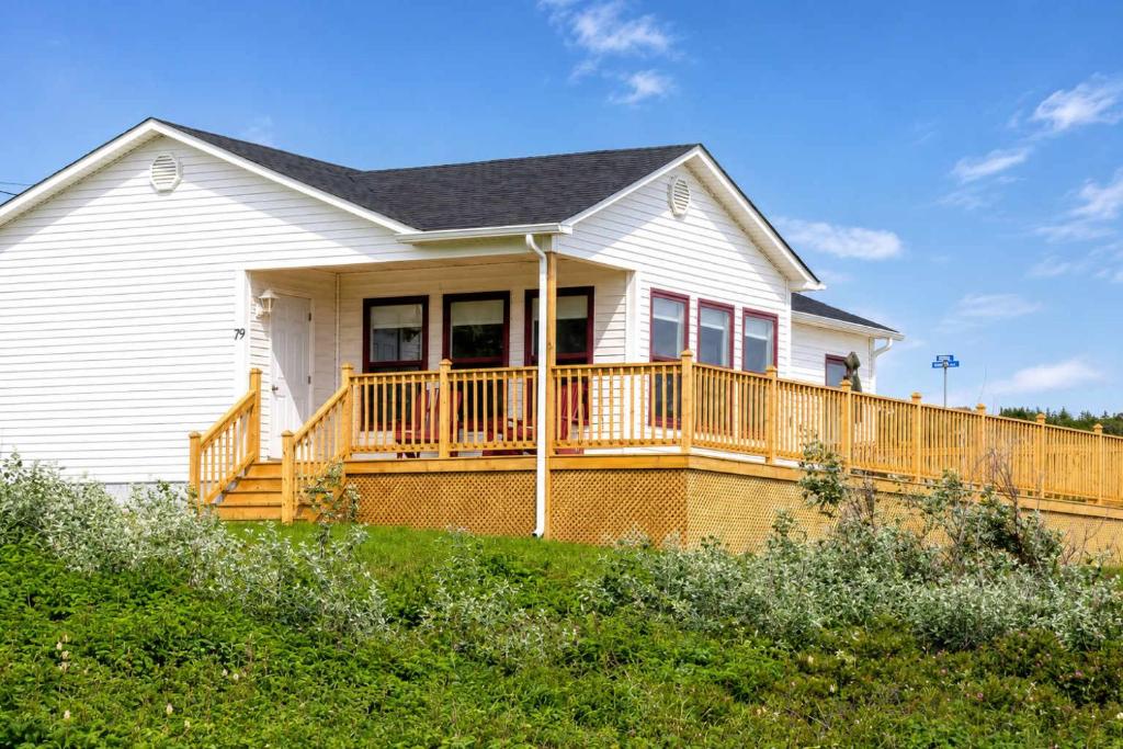 a white house with a large wooden deck at Whistler's View in Twillingate