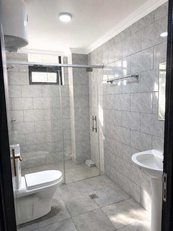 a bathroom with a shower and a toilet and a sink at Kigali Sky Light Homes in Kigali