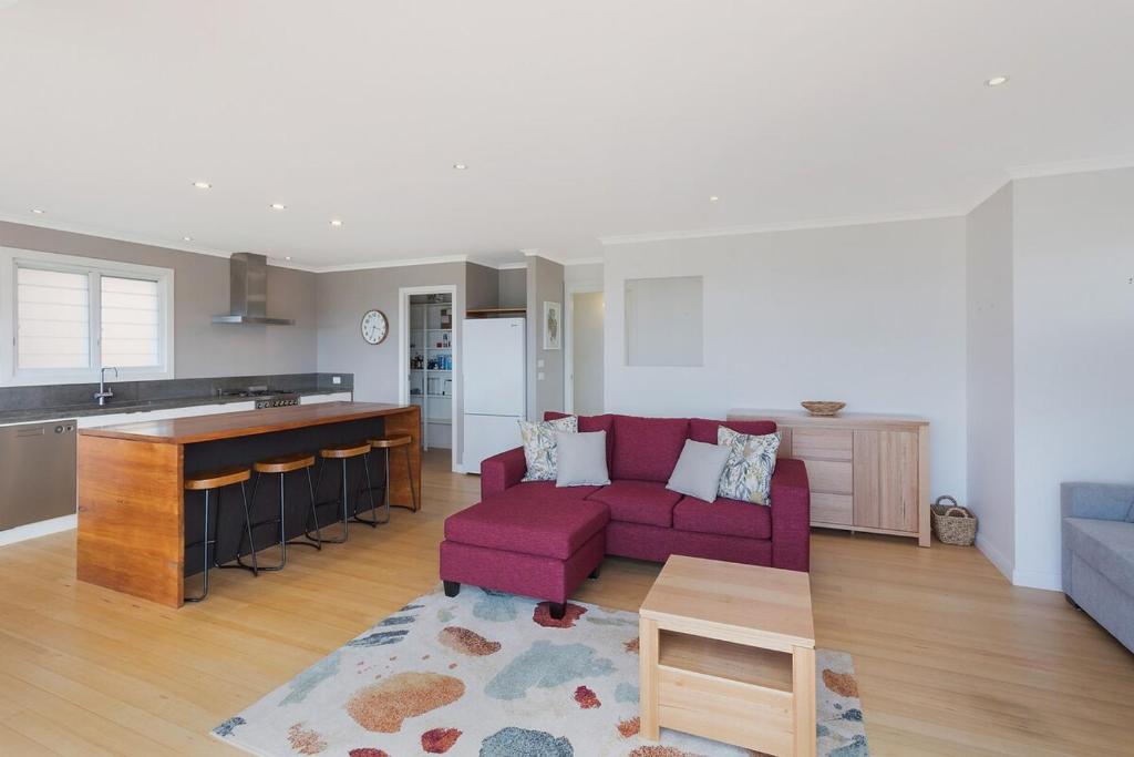 a living room with a purple couch and a kitchen at Wild Views in Tathra