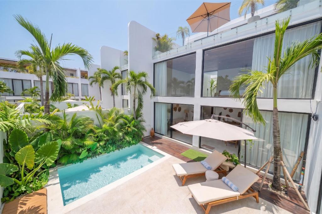 an exterior view of a building with a swimming pool and palm trees at Darina Villa - Private Rooftop Escape with Pool Close to Beach in Badung