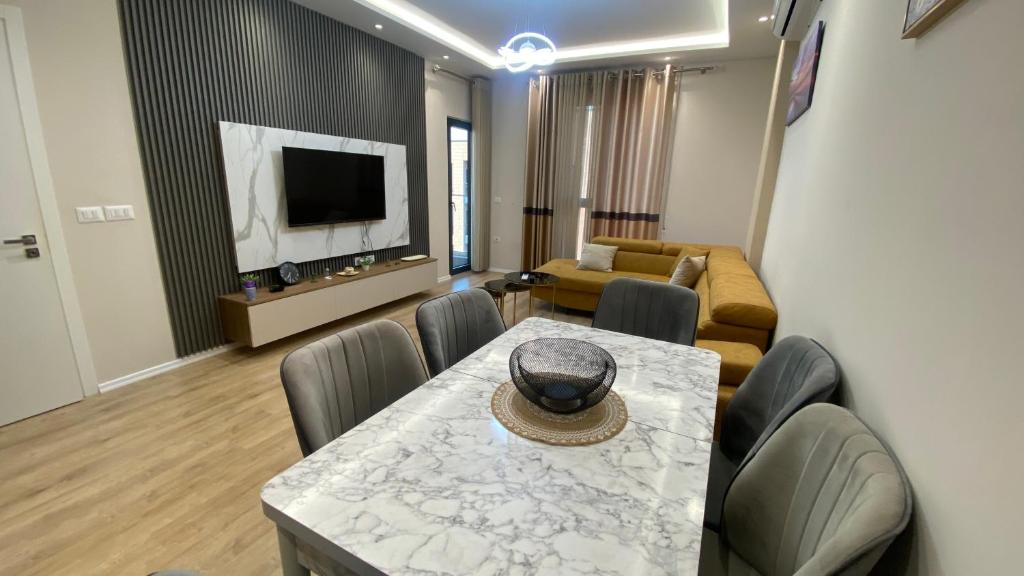 a living room with a table and chairs and a television at SL Apartment in Tirana