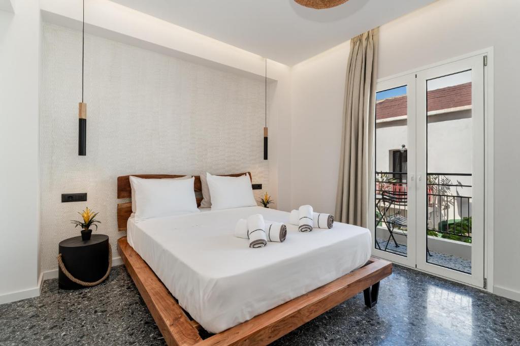 a bedroom with a large white bed and a balcony at Maistrali city suites in Agios Nikolaos