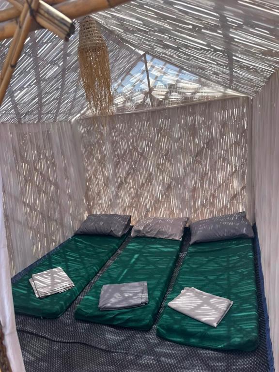 a tent with a green bed with four pillows at Chalets MB in Tarîfa
