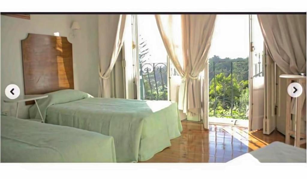 a bedroom with two beds and a large window at Monte da Lua in Sintra