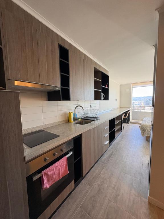 a kitchen with wooden cabinets and a large window at Studio cómodo y luminoso, a pasos del centro! - Bilingual Support Eng, Esp in Concepción