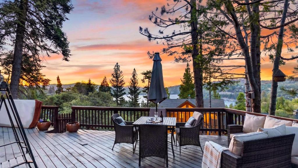 a deck with a table and chairs and an umbrella at Emerald Overlook by AvantStay in Lake Arrowhead